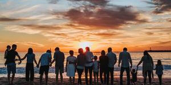 Family and friends of all ages holding hands on beach